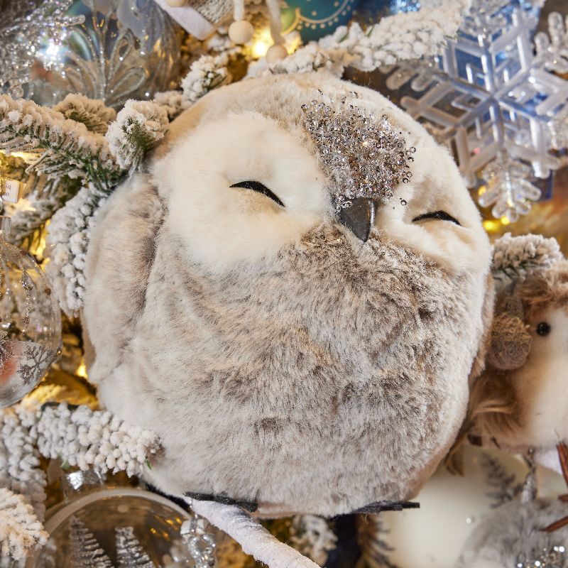 Furry owl ornament among frosted branches