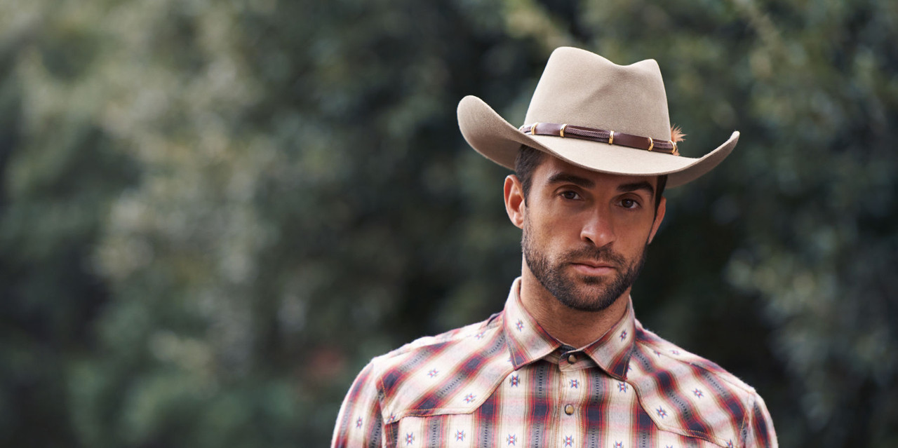 Western man with cowboy hat and western clothing standing in the forest