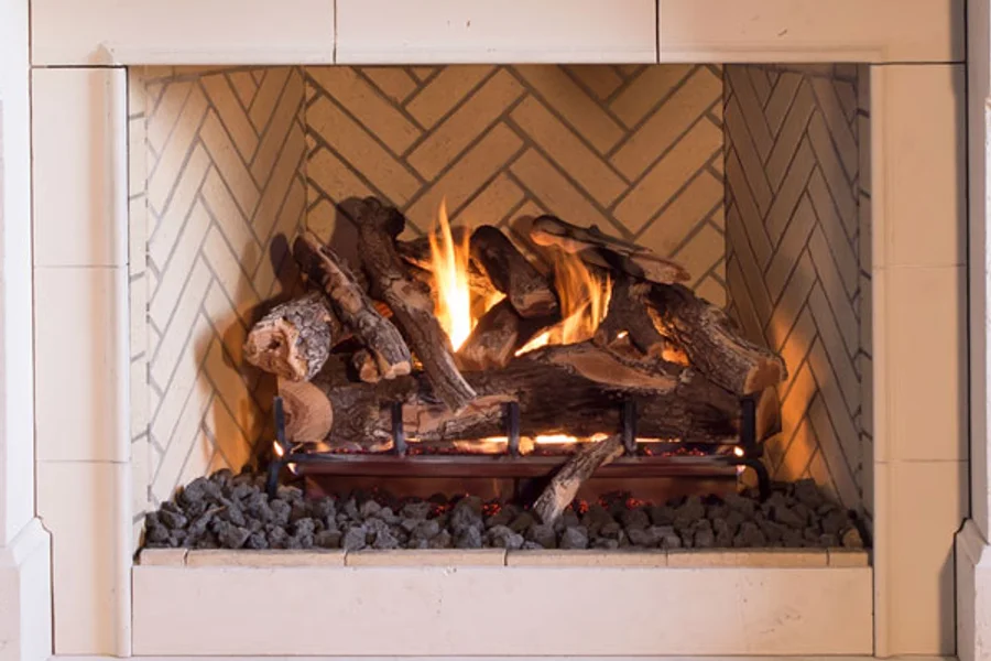 Burning gas log set inside a fireplace with a herringbone brick interior and light stone surround