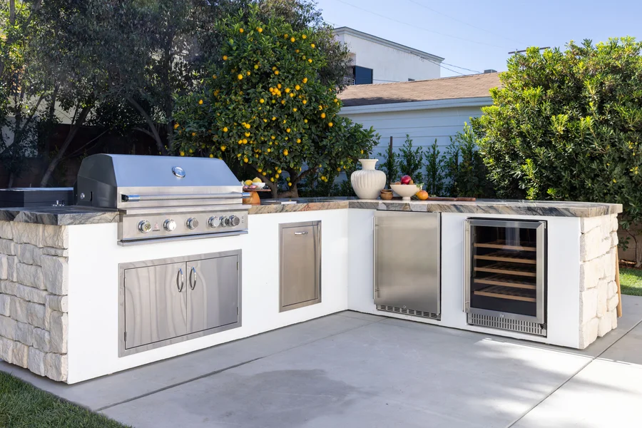 Outdoor kitchen with a built-in stainless steel grill, storage cabinets, refrigerator, and wine cooler