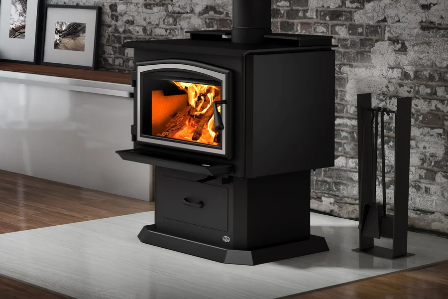 Black wood-burning stove with visible flames on a hearth beside an exposed brick wall