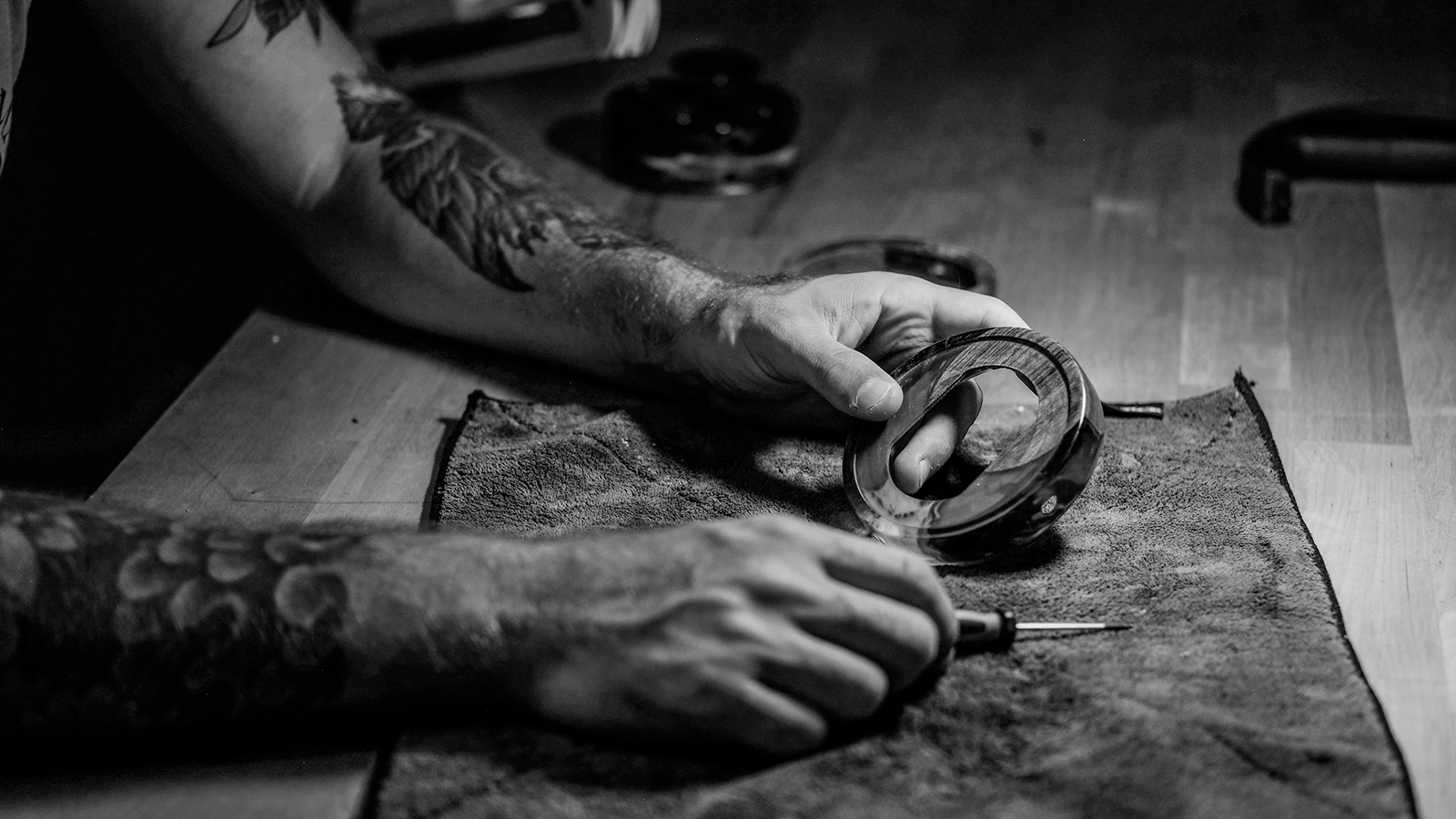 hands holding a headphone component and screwdriver on a workbench