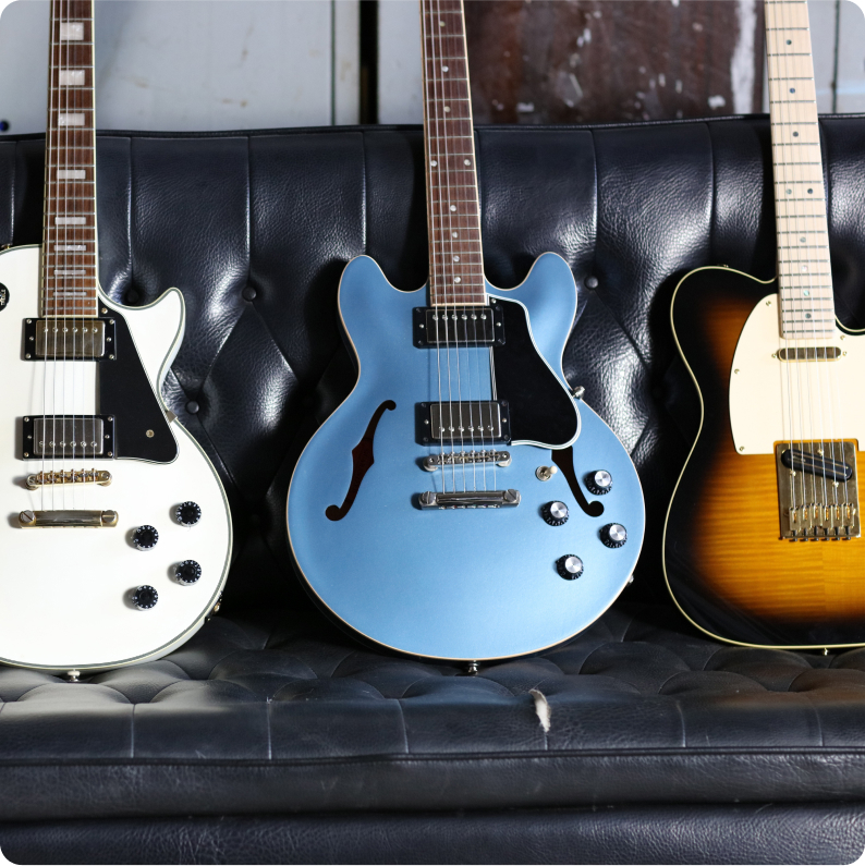 electric guitars lined up on a leather couch