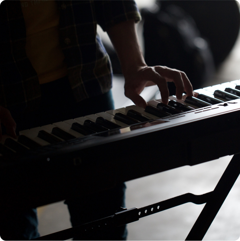 Musician playing an electric keyboard in a dark room