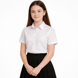 A teenage girl, approximately 14 years old, is shown wearing the Ayra Girls' Short Sleeve School Blouse in white, paired with a classic black pleated school skirt. The blouse is crisp and smart, featuring a clean, pocketless design ideal for school uniform requirements. This image is set against a pure white background, offering a clear and professional view of the product fit and style—perfect for showcasing the blouse as part of a complete school uniform.