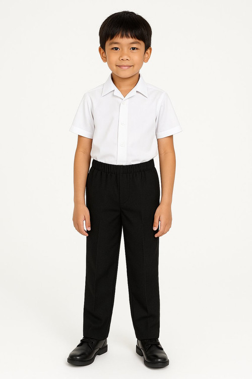An 8-year-old Asian boy dressed in full elasticated black school trousers and a white short-sleeve shirt, smiling calmly against a clean white backdrop.