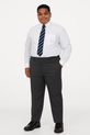 Portrait of a slightly plus size teenage boy wearing charcoal grey school trousers, white shirt, and striped tie, standing confidently with one hand in his pocket on a pure white background.