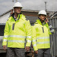 Hi vis yellow hooded softshell safety coat with printed safety bands and zip through collar