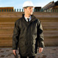 Black waterproof managers jacket with stud storm flap, front pockets and a stand-up collar