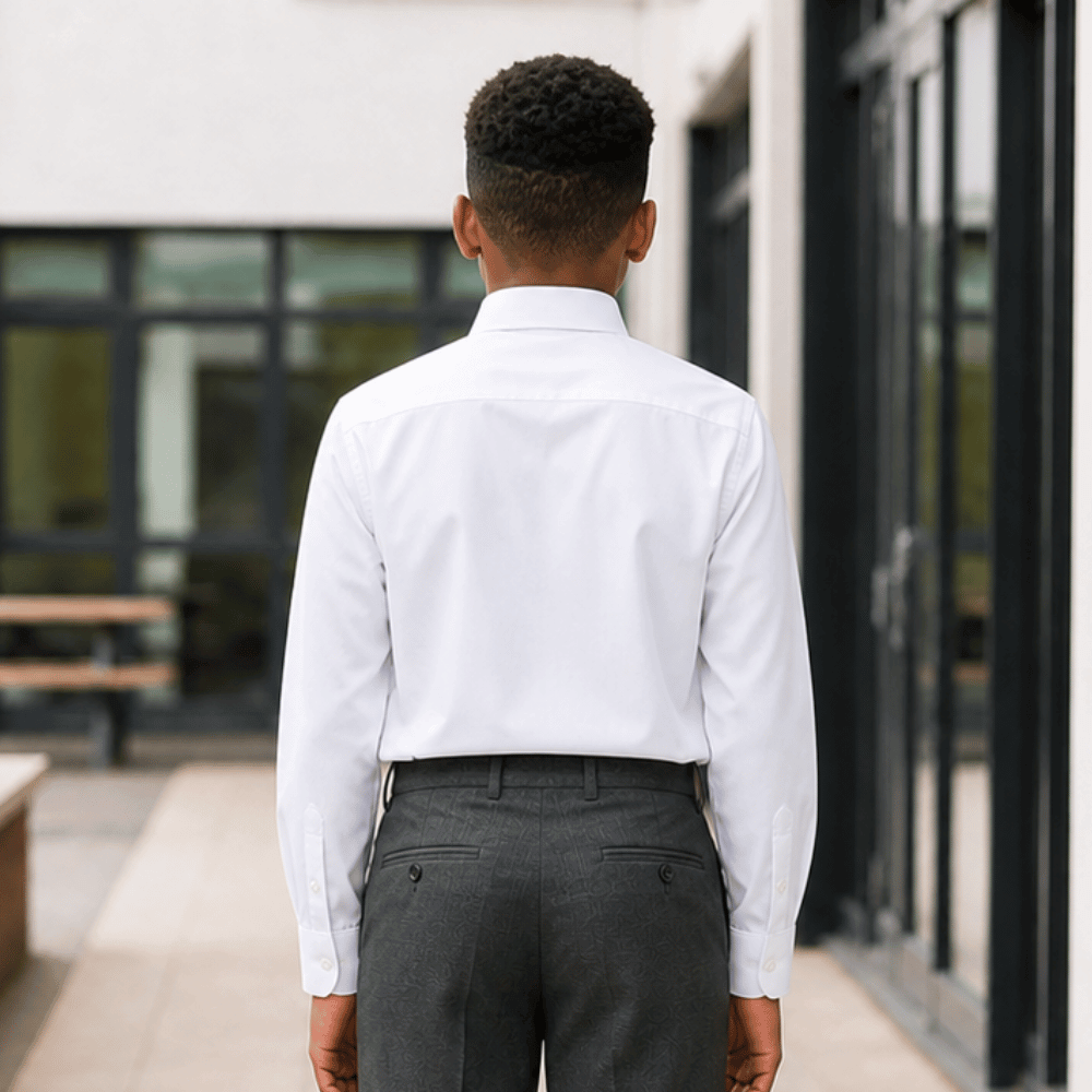Back view of boy wearing white long sleeve non iron school shirt with grey school trousers