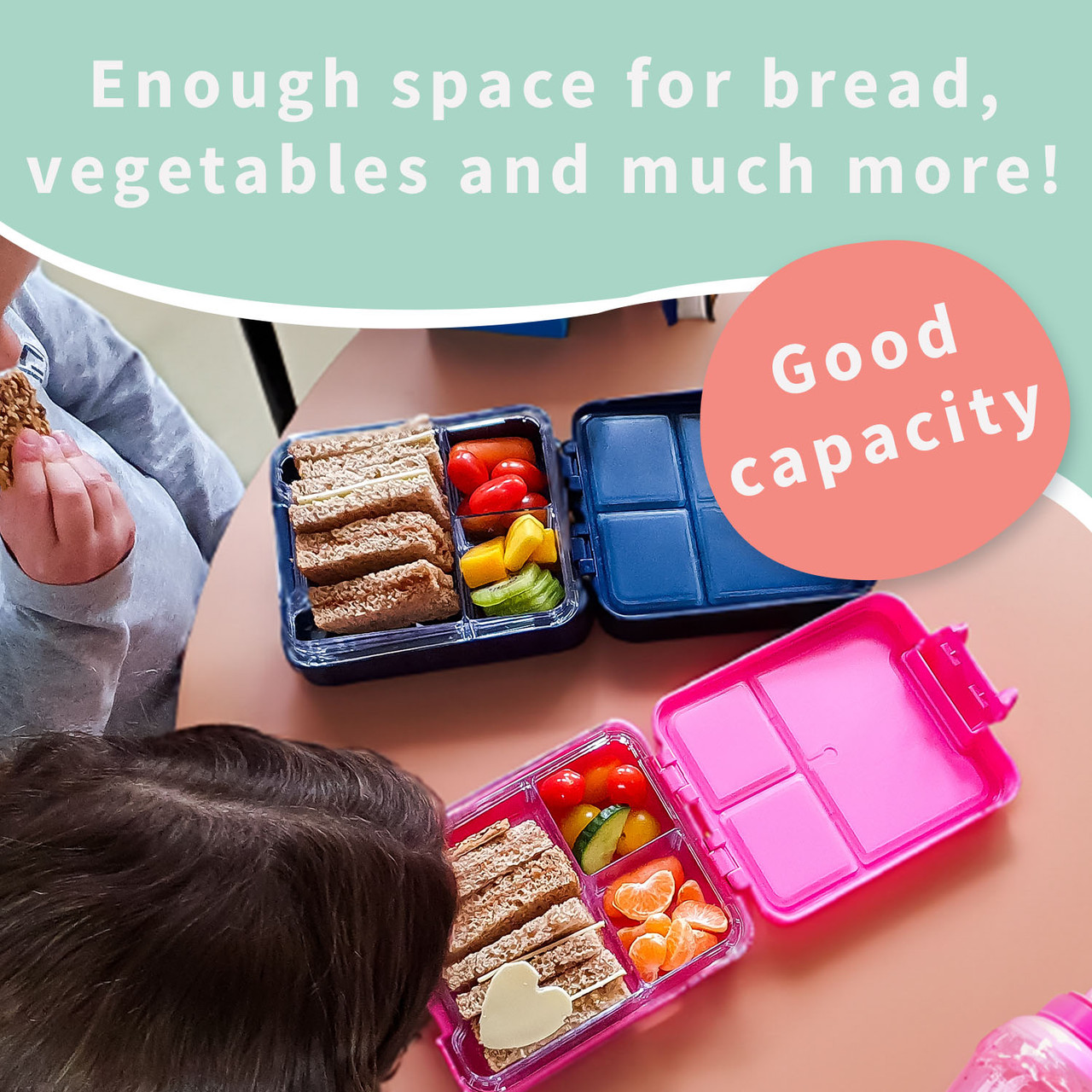 Two kids lunch boxes open with sandwiches, fruit and vegetables in their compartments