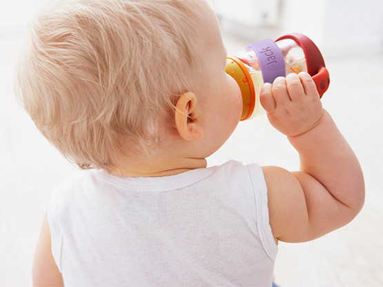 Toddler drinking from a cup with a personalised name band