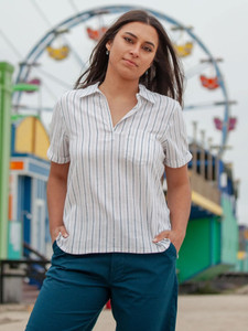 Woman standing in front of carnival wearing Breezy Popover Camp Shirt in white