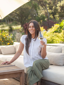 Woman sitting outside with wine wearing Pippin Pintuck Top in white swiss dot