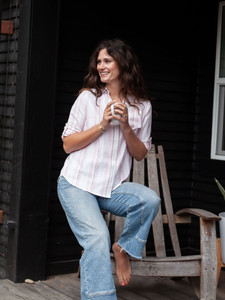 Woman sitting on stool outside with wine wearing Plumas Y-Neck Shirt in Rose