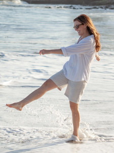 Woman kicking up water on beach wearing Beachcomber Patterned Long Sleeve Popover in Stone Gray