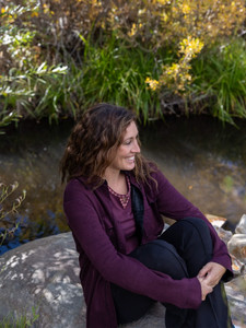 Woman sitting outside during fall wearing the Arctic Whisper Raglan Embroidered Top in fig purple.