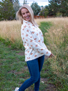 Woman standing in field during fall wearing the Lucy Drift Printed Microfleece Pullover studio in white.