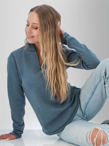 Woman sitting in studio wearing the Cascade 1/4 Zip Striped Pullover in sky captain blue.