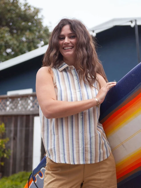 Woman standing with surfboard wearing Aviva Full Button Striped Tank Top in Ceramic Stripe