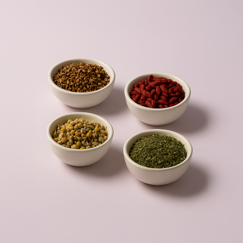 Four bowls of chamomile flowers, skullcap herb, goji berries, and licorice root arranged on a soft pink background.