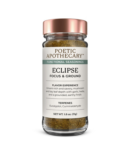 The jar features a premium copper-colored metallic lid and a minimalist cream-colored label with black and slate-gray typography. The brand name "POETIC APOTHECARY™" is displayed at the top, followed by the product name "ECLIPSE" and the functional benefit "FOCUS & GROUND". The label includes sections for "FLAVOR EXPERIENCE," describing an umami-rich, savory profile with mushroom, bay leaf, and garlic, and a "TERPENES" section listing Eucalyptol and Cuminaldehyde. Visible contents consist of a finely ground, textured spice blend with a deep, earthy-brown hue. Soft, even lighting casts a gentle shadow at the base, emphasizing a high-end apothecary aesthetic.