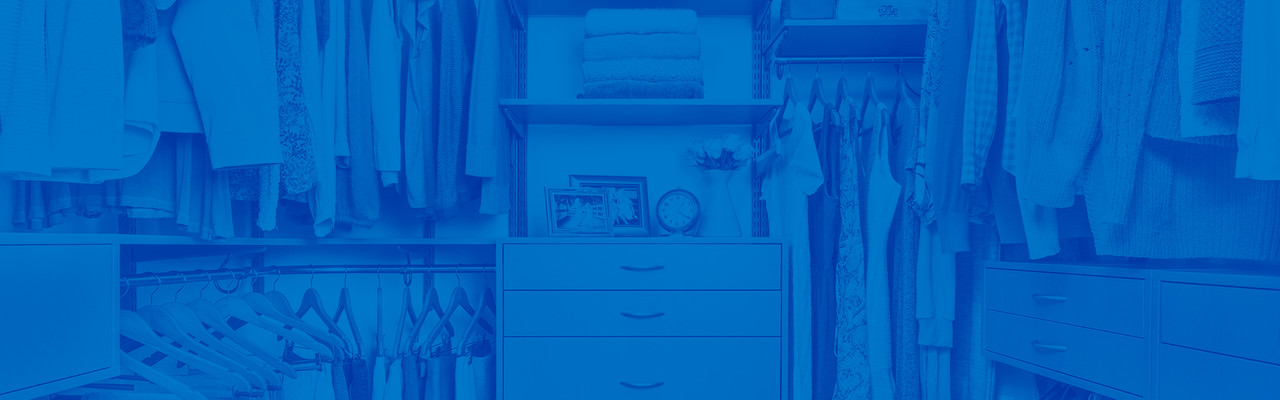 This is an Organized Living freedomRail closet propped with clothing. In the center are OBox Drawers and shelves with picture frames. This image has a blue overlay on the entire image. 