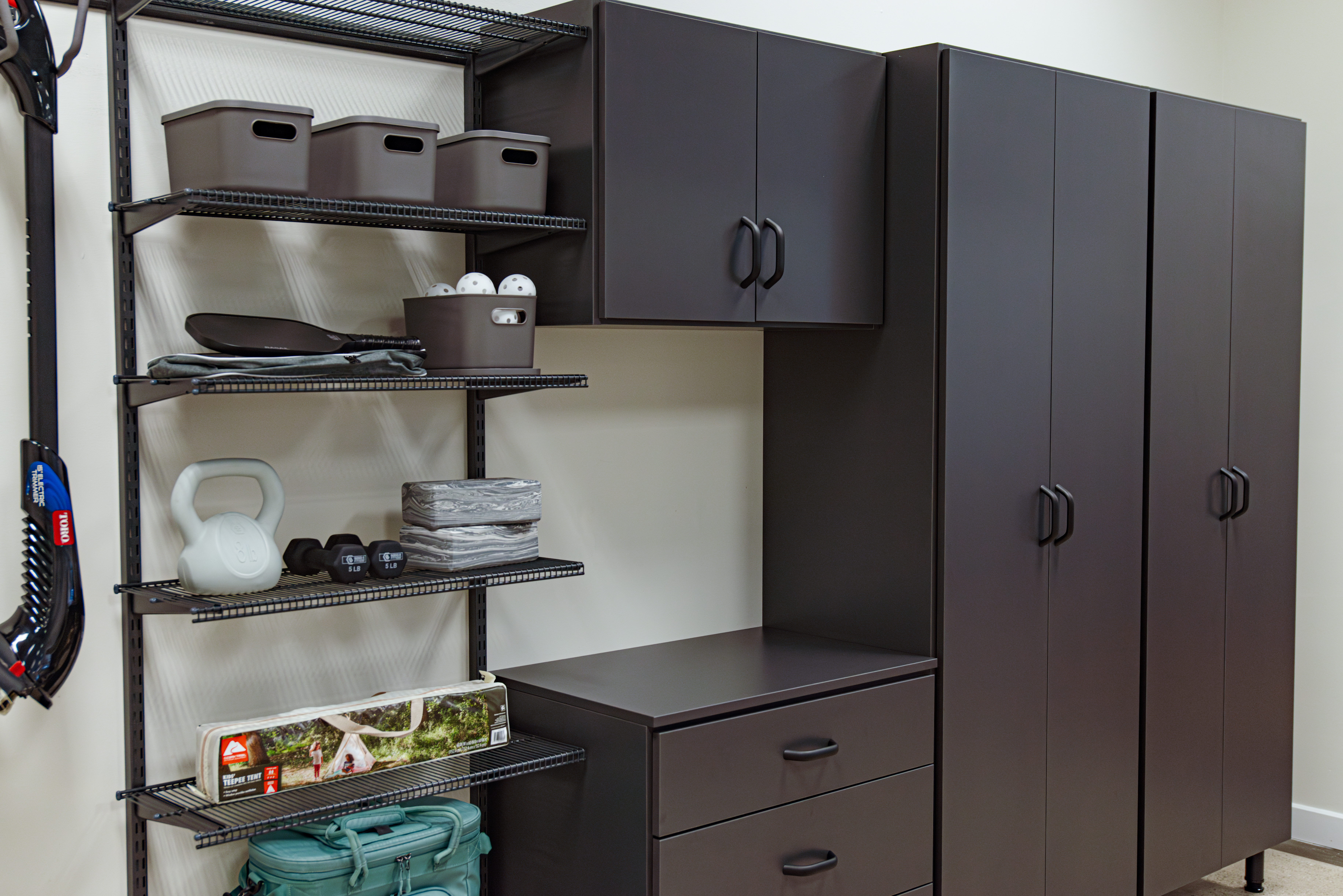 This is an Organized Living freedomRail EDGE modular storage system with Slate cabinets and granite gray ventilated shelves. The walls are white and the shelves are holding bins and sports gear.