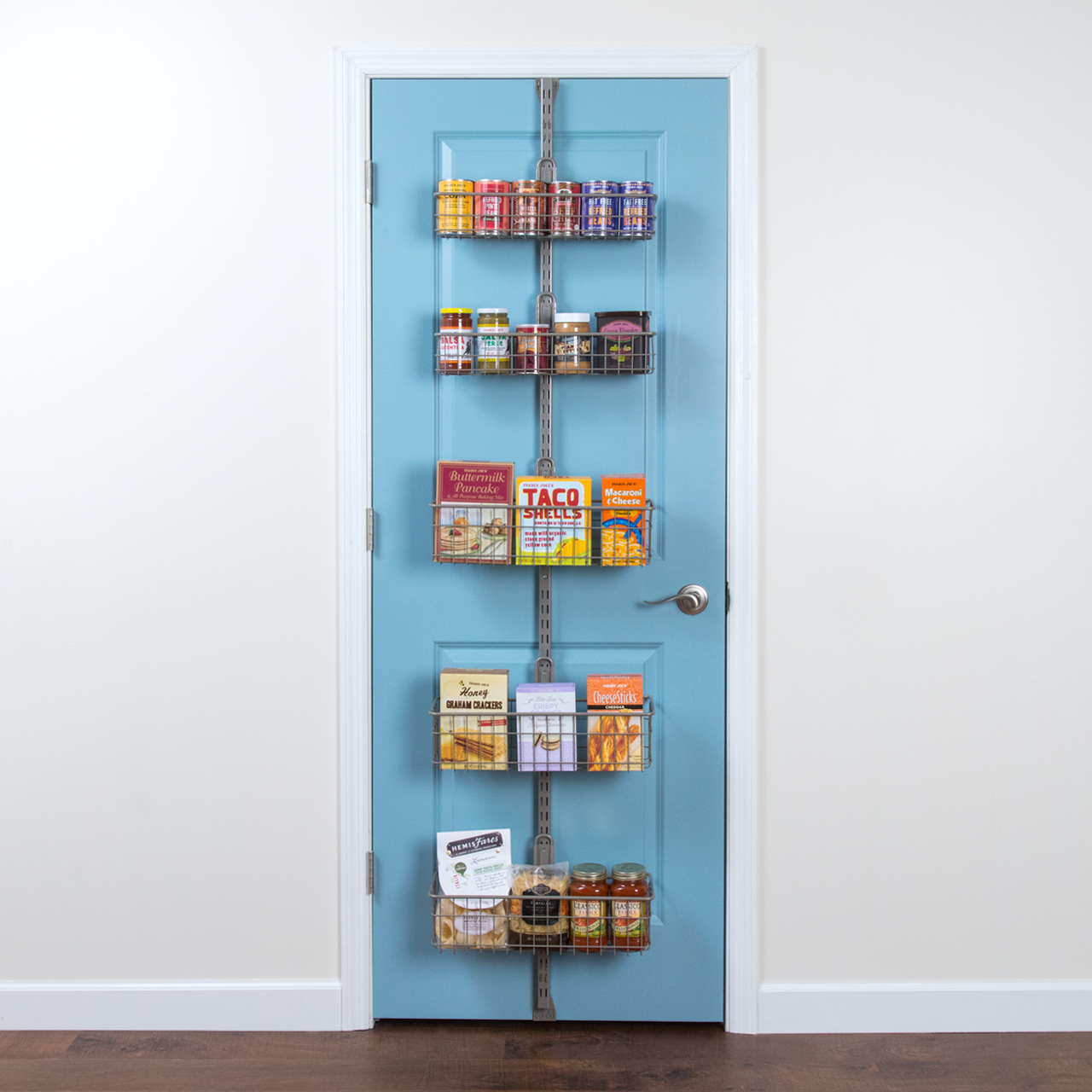 #Over the door pantry in nickel finish on a light blue door featuring baskets with pantry items such as canned food and boxed pasta