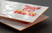 Painted edge business card with a vivid orange edge and bold red-and-orange logo print on premium cardstock — printshaQ.com