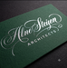 This elegant cotton business card pairs a deep forest-green cotton stock with a silver matte foil stamp on the flowing script logo. The matte finish keeps the foil subtle and refined rather than flashy — a soft shimmer instead of a shine — while the cotton's natural texture adds warmth behind the lettering. A strong fit for architecture, design, and other creative-professional brands that want a card as considered as their work.