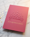 Spot UV quinceañera invitation in deep rose cardstock with a glossy tiara and star design and "Mis Quince Años" lettering, styled with gold star confetti on marble.
