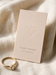 Blind embossed business card in blush ivory cardstock with a raised diamond outline for a fine jewelry designer, styled with a gold ring on ivory linen.


