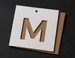 Die cut hang tags with letterform M cut-through on kraft | printshaQ