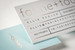 Elegant white business cards featuring soft rose-gold foil stamping, minimalist typography and a coordinating light-blue reverse side.