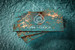 Distinctive teal business cards with bright copper foil stamping across the logo, lettering and textured abstract background design.