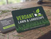 Photorealistic landscaping business card for Verdant Lawn and Landscape on a wood background featuring a macro grass blade image and services list.