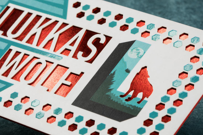 Custom foil stamped business cards featuring reflective red foil, bold printed colors and precision laser die-cut hexagon details for a distinctive, high-end finish.