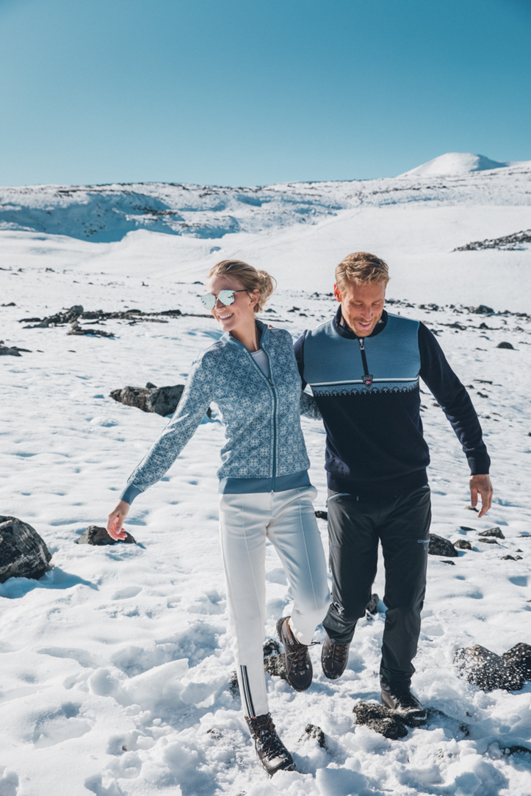 Woman and man standing in snow wearing Dale of Frida ladies cardigan in Blue Shadow/Off White/Grau Vig/Atlantic Mele, 82931-D and Lahti mens sweater in Navy/Blue Shadow/Off White, 93241-D