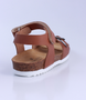 Tan girls leather sandal with buckle front strap, hook‑and‑loop ankle strap and cork‑textured sole.