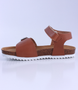 Tan girls leather sandal with buckle front strap, hook‑and‑loop ankle strap and cork‑textured sole.