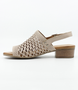 Beige women’s laser‑cut leather sandal with adjustable strap and low block heel.