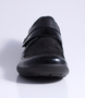 Black women's leather and fabric comfort shoe with textured panels, hook-and-loop strap and cushioned footbed.