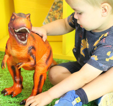 Child playing with out jumbo red T-Rex Dinosaur toy figure
