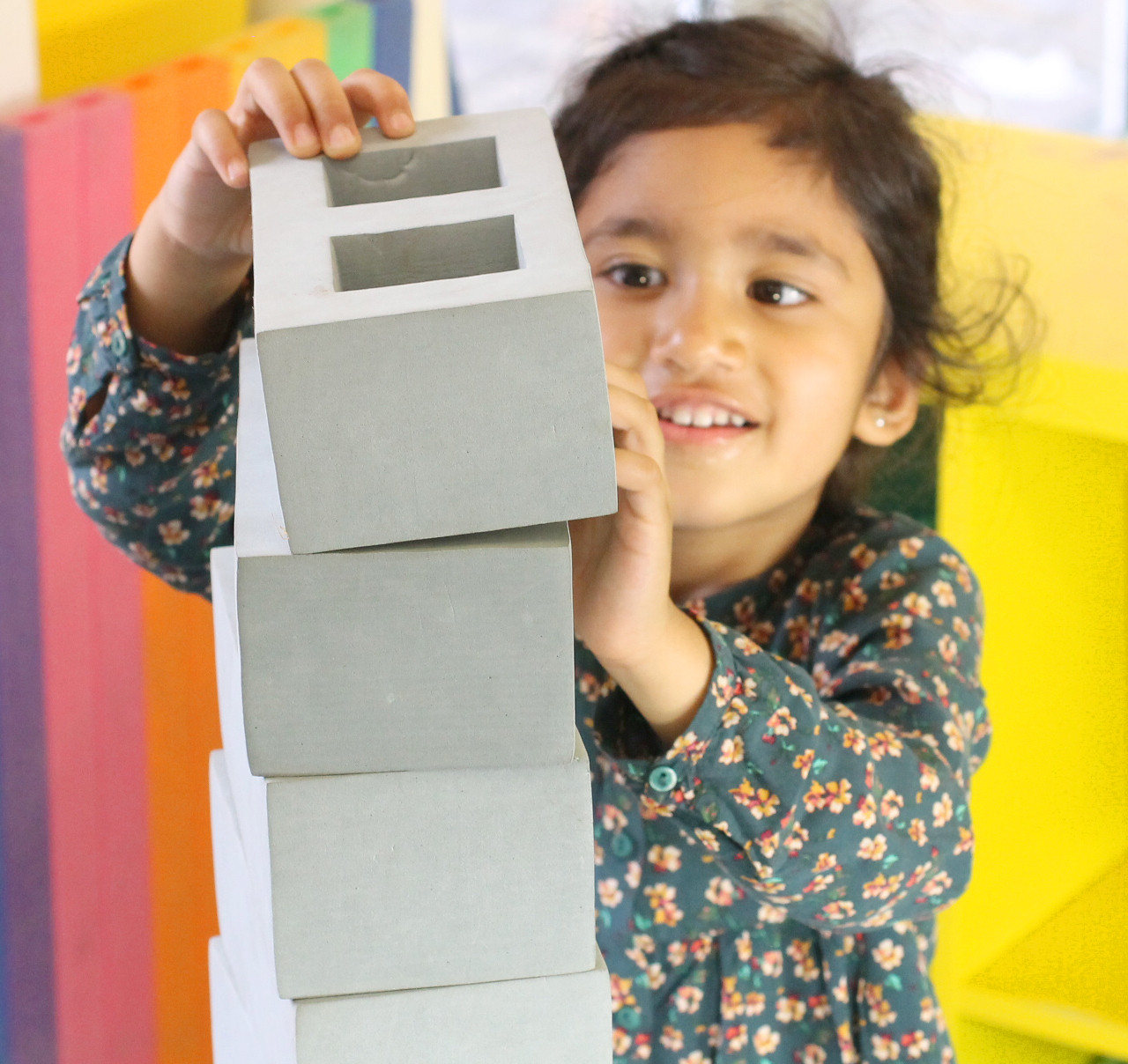 Child stacking grey brick
