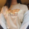 fragile tee in khaki with the picture of three baby angels