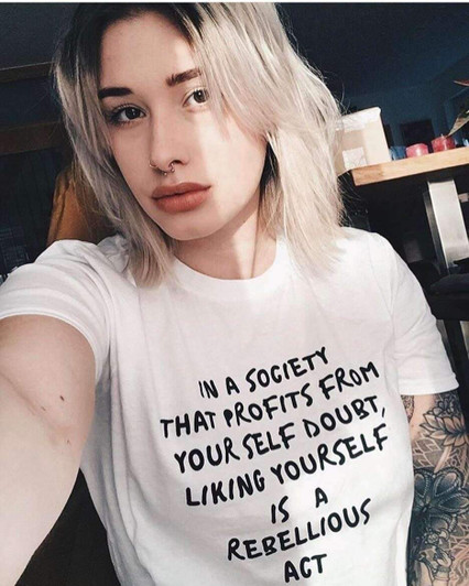 in a society that profits from your self doubt, liking yourself is a rebellious act white tee