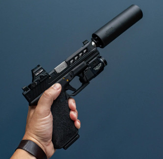 A hand holding a Glock 19 with a True precision threaded barrel in Stainless, with a black suppressor