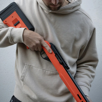 A person holding the TRUE Hunter TP/22 with black nitride bull barrel and Hunter Orange stock. A person holding the TRUE Hunter TP/22 with black nitride bull barrel and Hunter Orange stock.