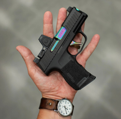 True Precision Sig P365 with Spectrum Non-Threaded barrel, extractor and True Trigger, being held over grey background.